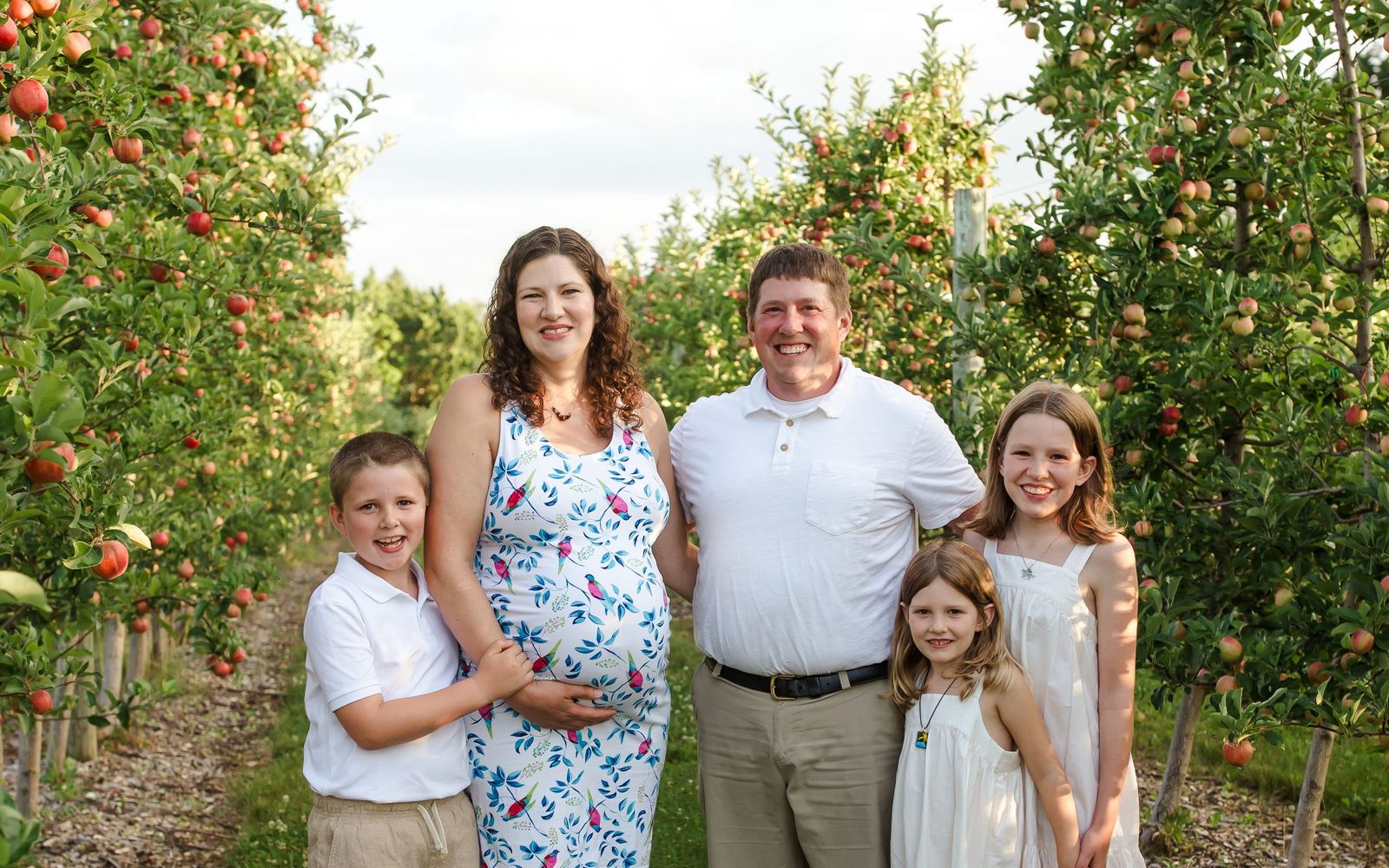 A family with three children outdoors among apple trees